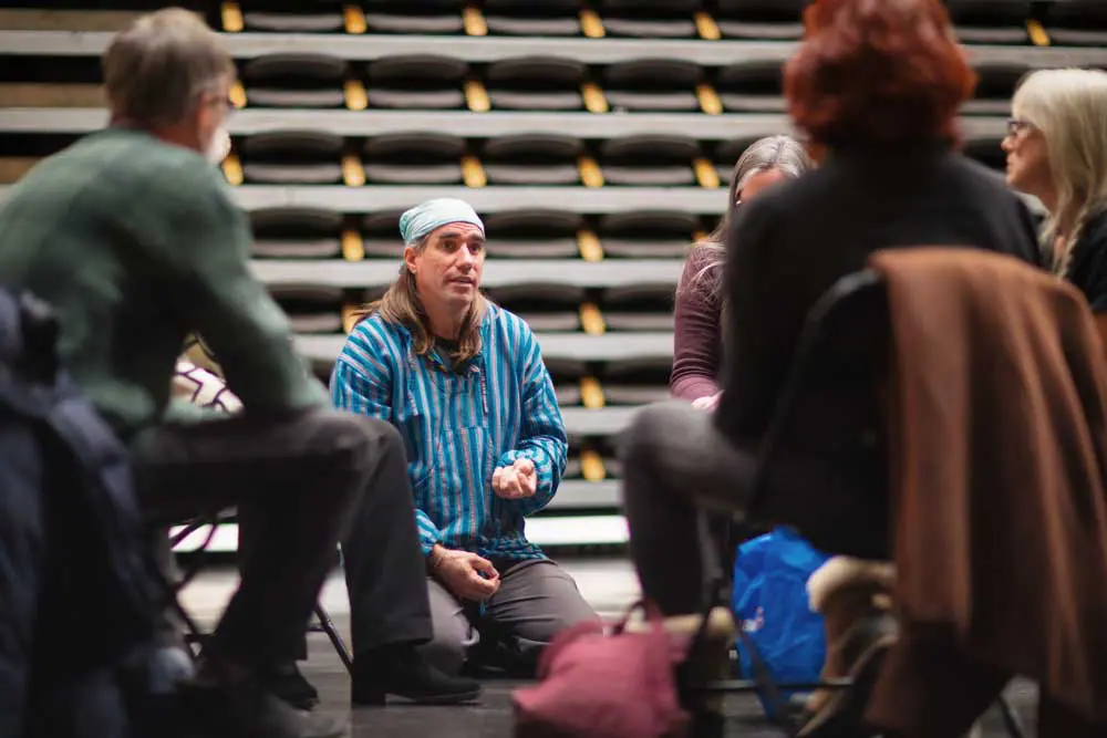 Group of people seated in a circle, possibly in a Design School workshop or class.